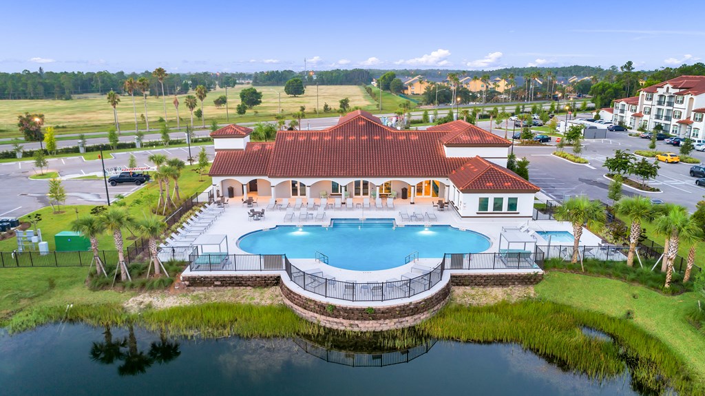 A large building with a red roof and a pool in front.