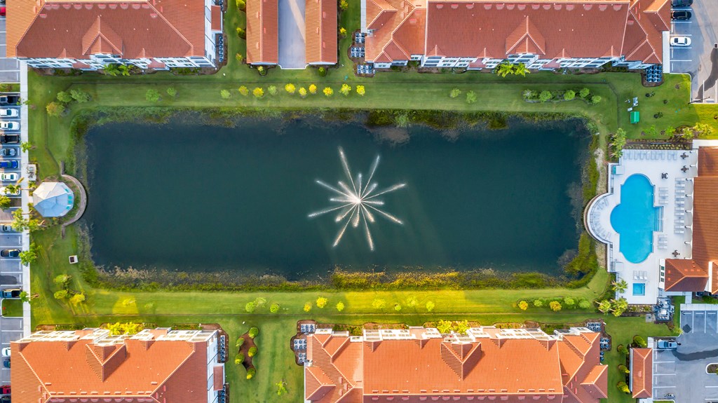A large lake surrounded by buildings and a fountain in the middle.