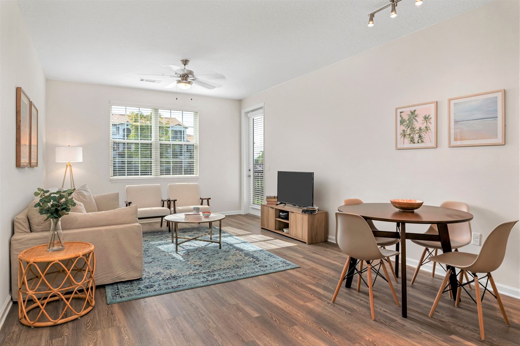 A living room with a television, a couch, a chair, a table, and a plant.