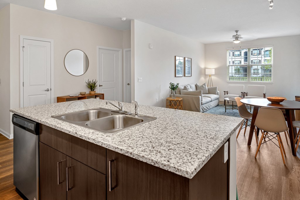 A kitchen with a marble countertop and a dining area with chairs.