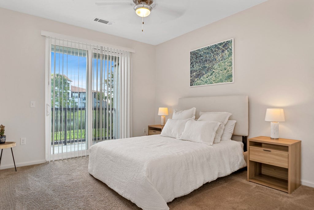A bedroom with a large bed, a nightstand, and a painting on the wall.