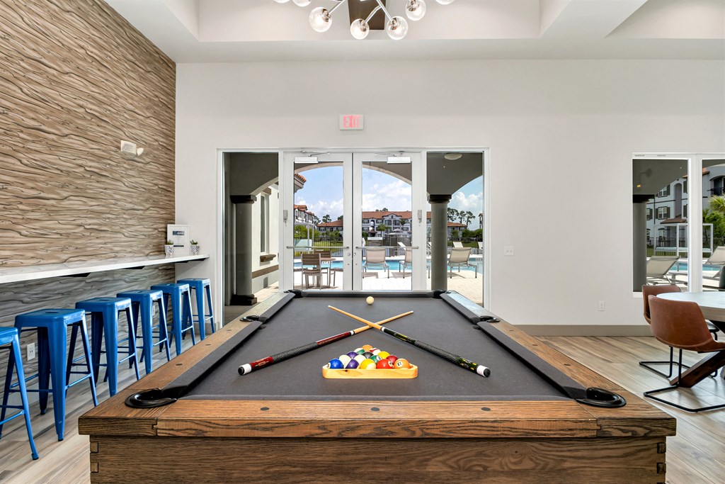A pool table in a room with a view of the outside.