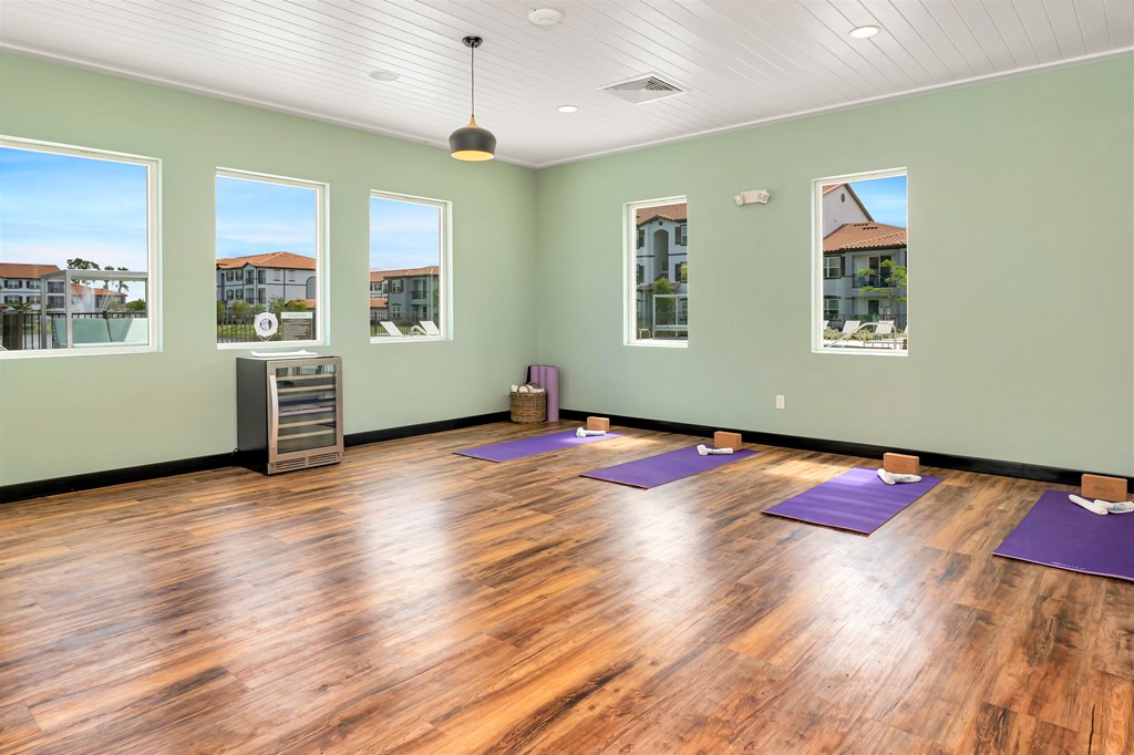 A yoga studio with purple mats and windows.