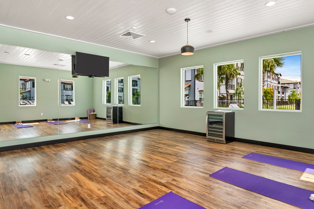 A yoga studio with purple mats on the wooden floor.