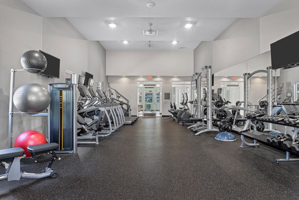 A gym with a variety of equipment including weights and a bench.
