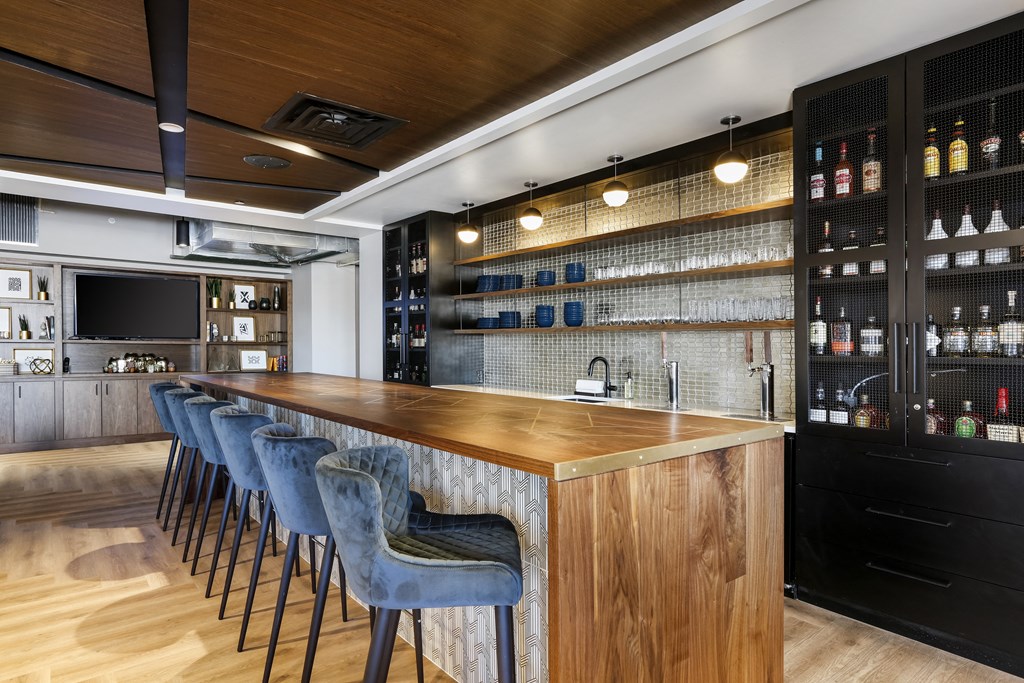 a bar in a restaurant with blue bar stools and bottles of alcohol on the