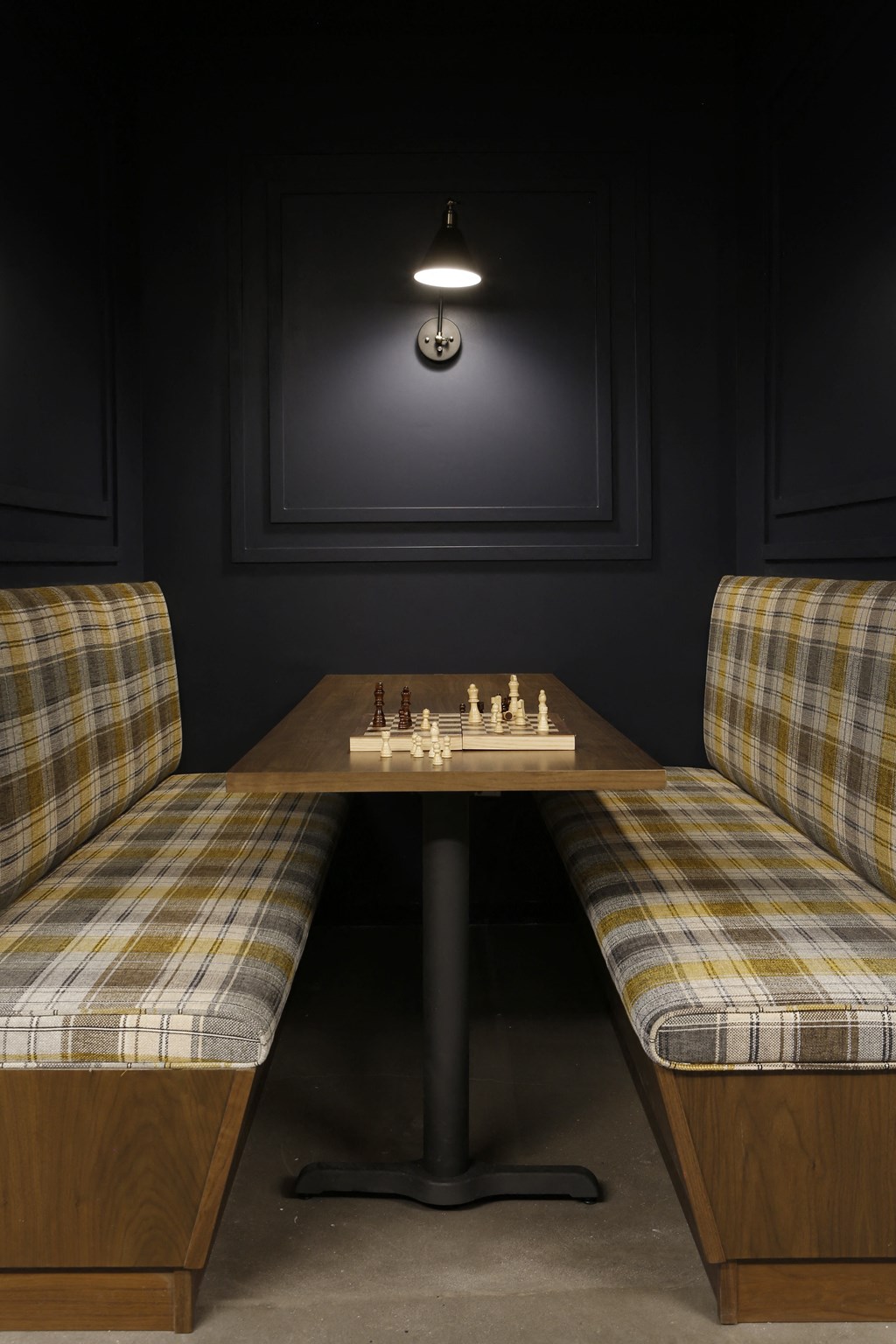 two plaid chairs and a chess table in a dark room