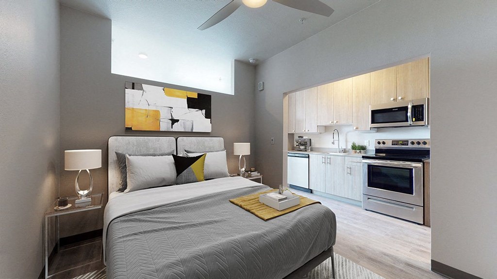 a bedroom with a bed and a kitchen in the background