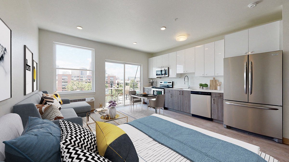 a bedroom with a bed and a kitchen in the background