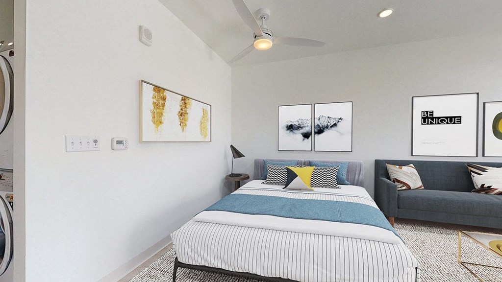 a bedroom with a bed and a couch in front of a washer and dryer