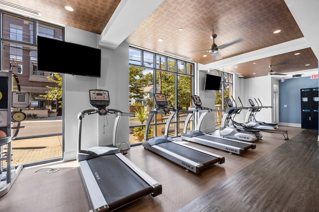 a gym with treadmills and televisions on the wall