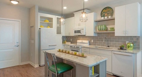 a kitchen with white cabinets and a marble counter top