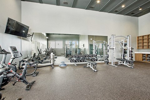 A spacious gym with a variety of equipment including treadmills, stationary bikes, and weight machines.