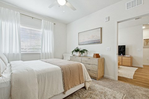 A bedroom with a large bed, a dresser, and a ceiling fan.