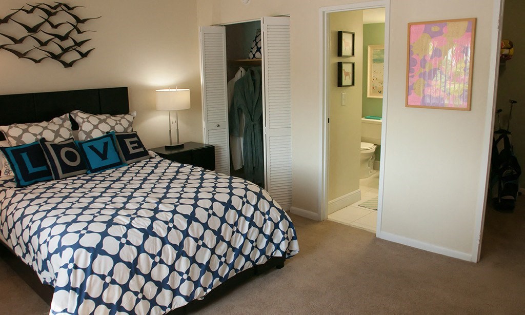 a bedroom with a large bed and a bathroom in the background