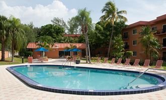 a resort style pool with chaise lounge chairs and palm trees in the background