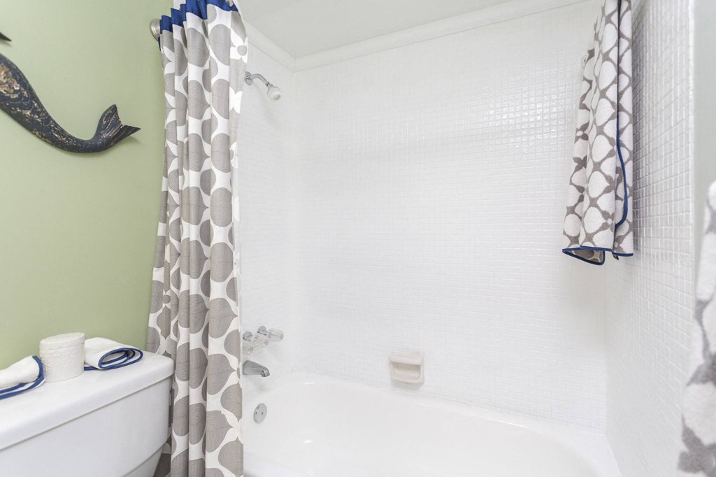 a bathroom with a white toilet next to a bathtub with a shower curtain