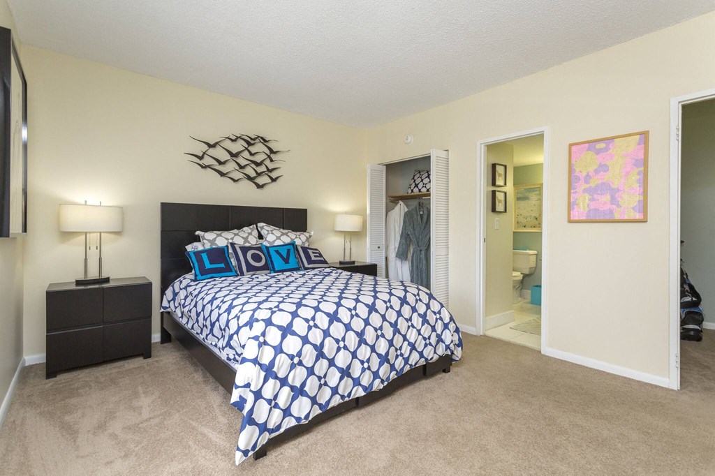 a bedroom with a large bed and a bathroom in the background