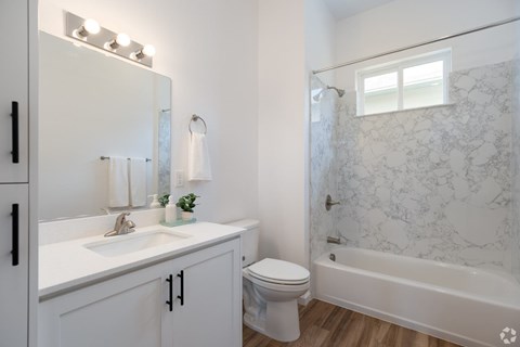 A white bathroom with a marble shower and a white toilet.