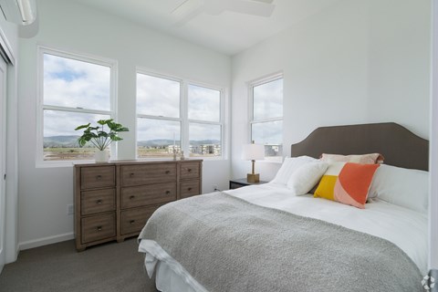 A bedroom with a large bed and a view of the mountains through the windows.