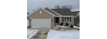 A house with a garage door and a driveway covered in snow.