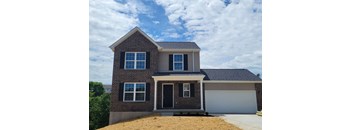 a brick house with a garage and a cloudy sky