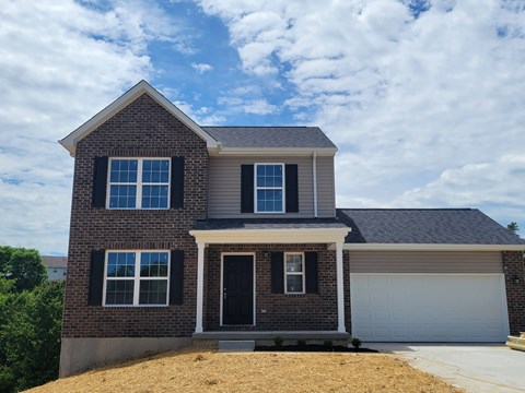 a brick house with a garage and a cloudy sky