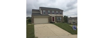 A house with a garage and a sign that says for rent.