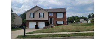 A two-story house with a garage is situated on a street.