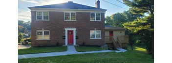 the front of a brick house with a red door
