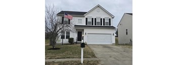 A white house with a black garage door and an American flag on the front.