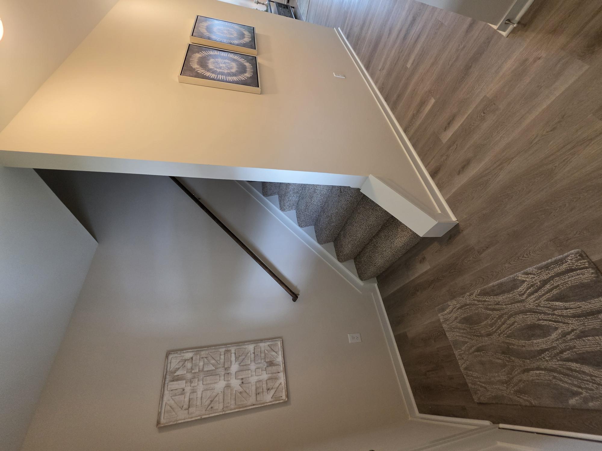 A staircase with a wooden handrail and a carpeted runner.