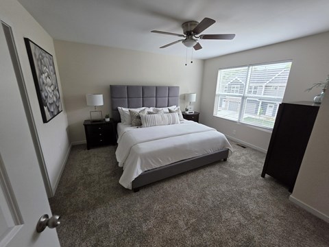 A bedroom with a bed, nightstands, and a ceiling fan.