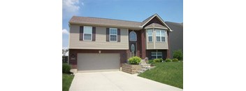A two-story house with a garage and a brick wall.