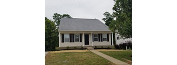 A small house with a grey roof and white siding.