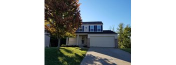A house with a garage and a tree in front.