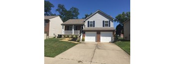 A house with a white garage door is in front of a tree.