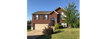 A house with a garage and a tree in front.