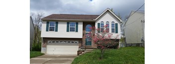 A house with a white garage door and a tree with pink flowers in front.