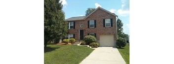 A brick house with a white garage door and black shutters.