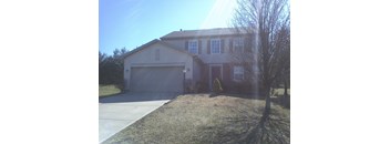 A house with a garage and a tree in front.