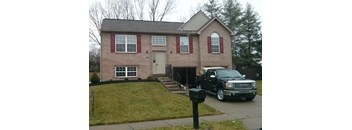 A house with red shutters and a black truck parked in front.