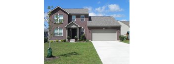 A house with a grey garage door and a tree in a green bag.