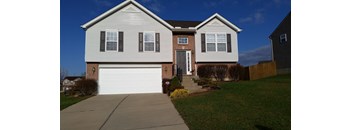 A two-story house with a garage door and a driveway.