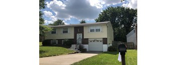 A two-story house with a garage and a mailbox in front.