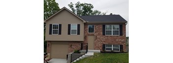 A house with a brown garage door and a brick wall.