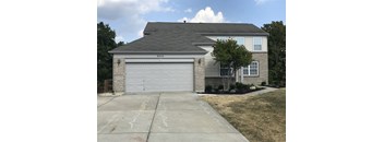 A house with a grey garage door and a brick wall.