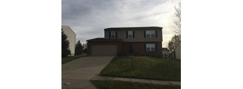 A house with a brown roof and a grey garage door.