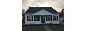 A small white house with a black roof and a front porch.