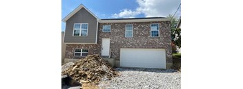 A house with a garage and a pile of gravel in front.